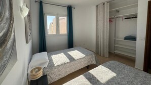 Un dormitorio con dos camas, una ventana y un armario.