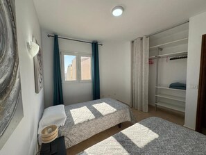 Ett sovrum med två sängar, ett fönster och en garderob.