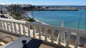 Un balcón con vistas a la costa, que incluye una playa, un muelle y barcos.
