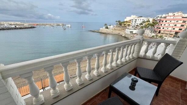 Un balcón con vista al mar, una mesa y dos sillas.