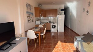 Un espacio habitable compacto con zona de comedor, kitchenette y cama.
