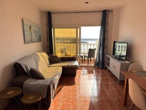 Ein Wohnzimmer mit einer Couch, einem Fernseher, einem Esstisch und einem Balkon mit Blick.