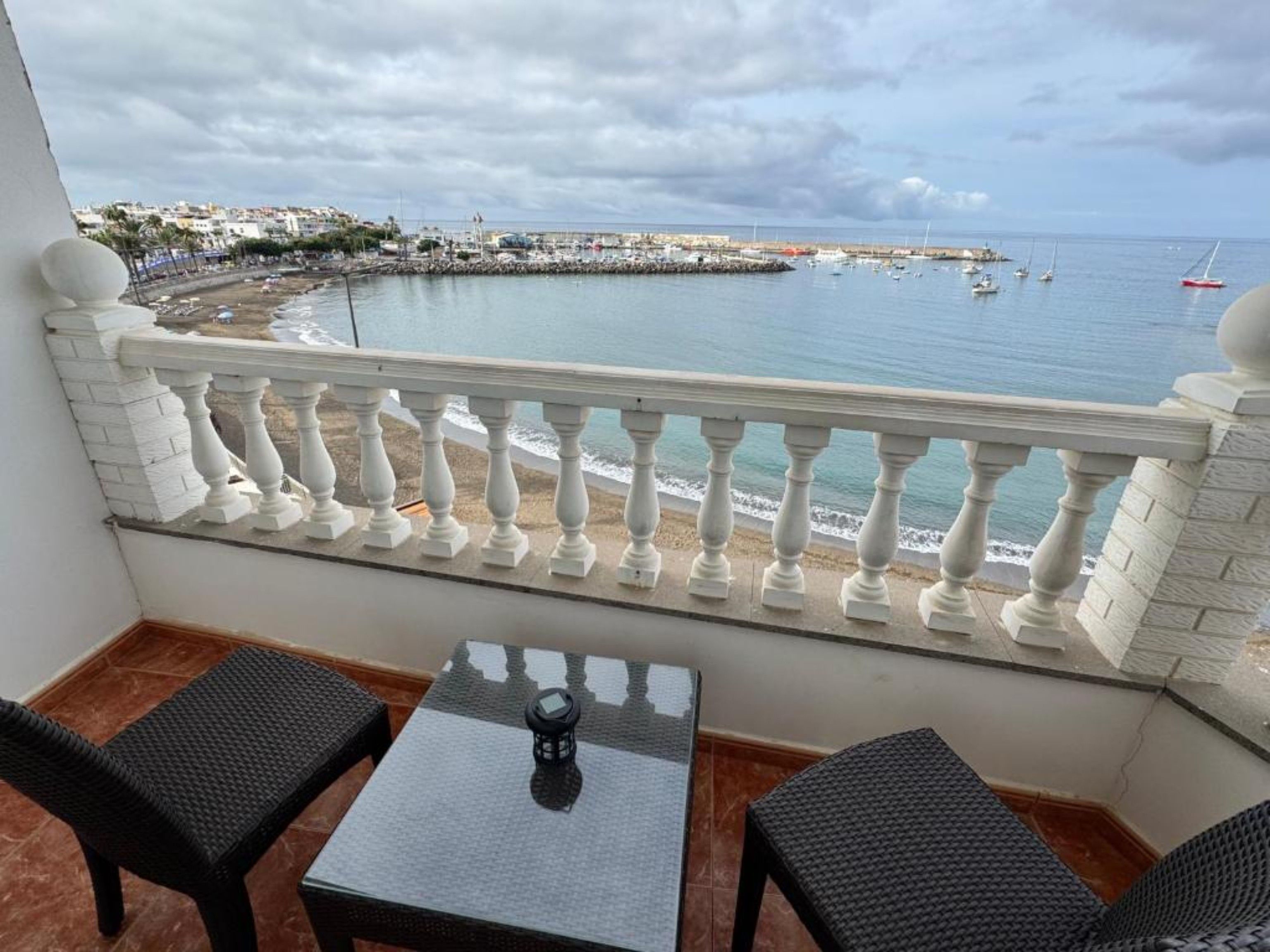 Un balcón con vista al mar, una mesa y dos sillas.