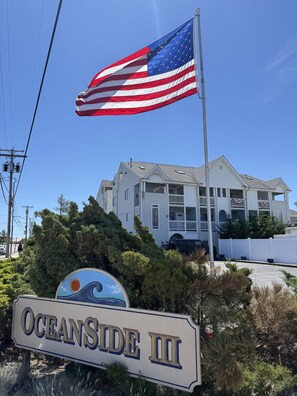 Un edificio con un letrero que dice 'OCEANSIDE III' y una bandera estadounidense.