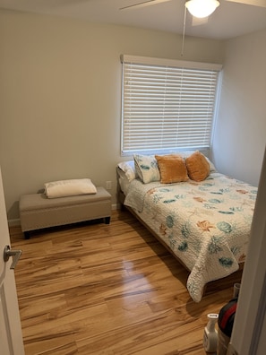 Un dormitorio con cama, un banco y una ventana con persianas.