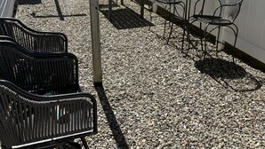 Ein Patio mit Tisch und Stühlen, umgeben von einem weißen Zaun und Kiesboden.