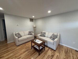 A living room with two sofas, a coffee table, and a floor lamp. - Ocean Block- Renovated 2 Bedroom 1 Bath Condo (Seaside Park)