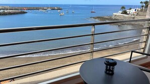 Un balcón con vista al mar, una mesa y una silla.