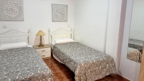 Un dormitorio con dos camas, una mesita de noche, una lámpara y dos relojes de pared.