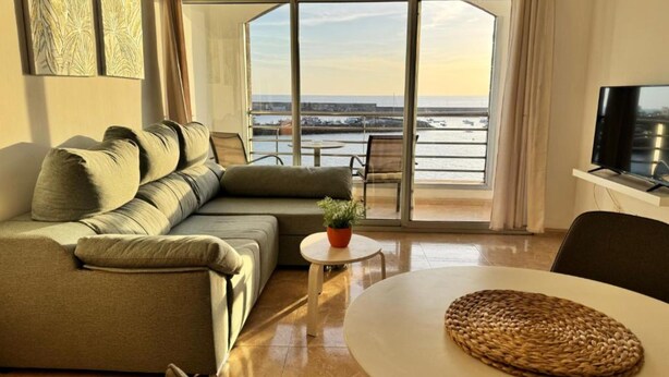 En moderne stue med sofa, et lille bord og et fjernsyn.