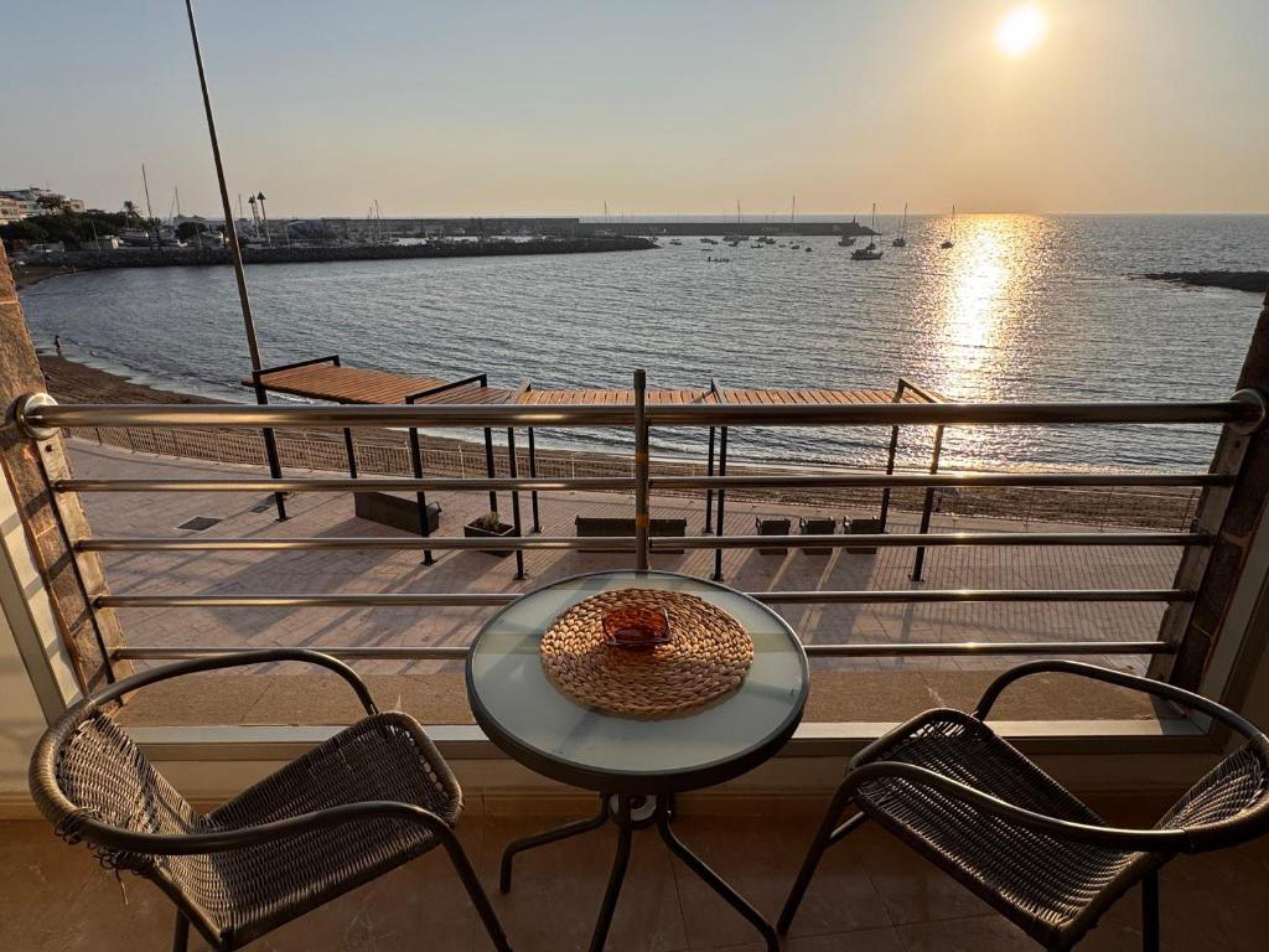 En balkon med to stole og et bord, der kigger ud over en bro med både og en kaj.