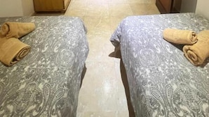 Habitació amb dos llits, un armari, una porta i una cortina.