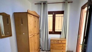 Un dormitorio con dos camas, un armario, una cómoda y una ventana con cortinas.