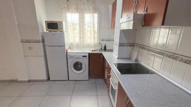 A compact kitchen with a washing machine, a microwave, and a sink.