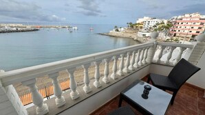 A balcony with a view of the sea, a table, and two chairs.