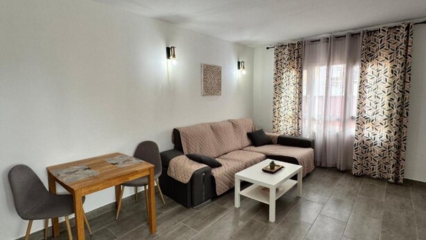 En moderne stue med sofa, sofabord og spisebord med stole.