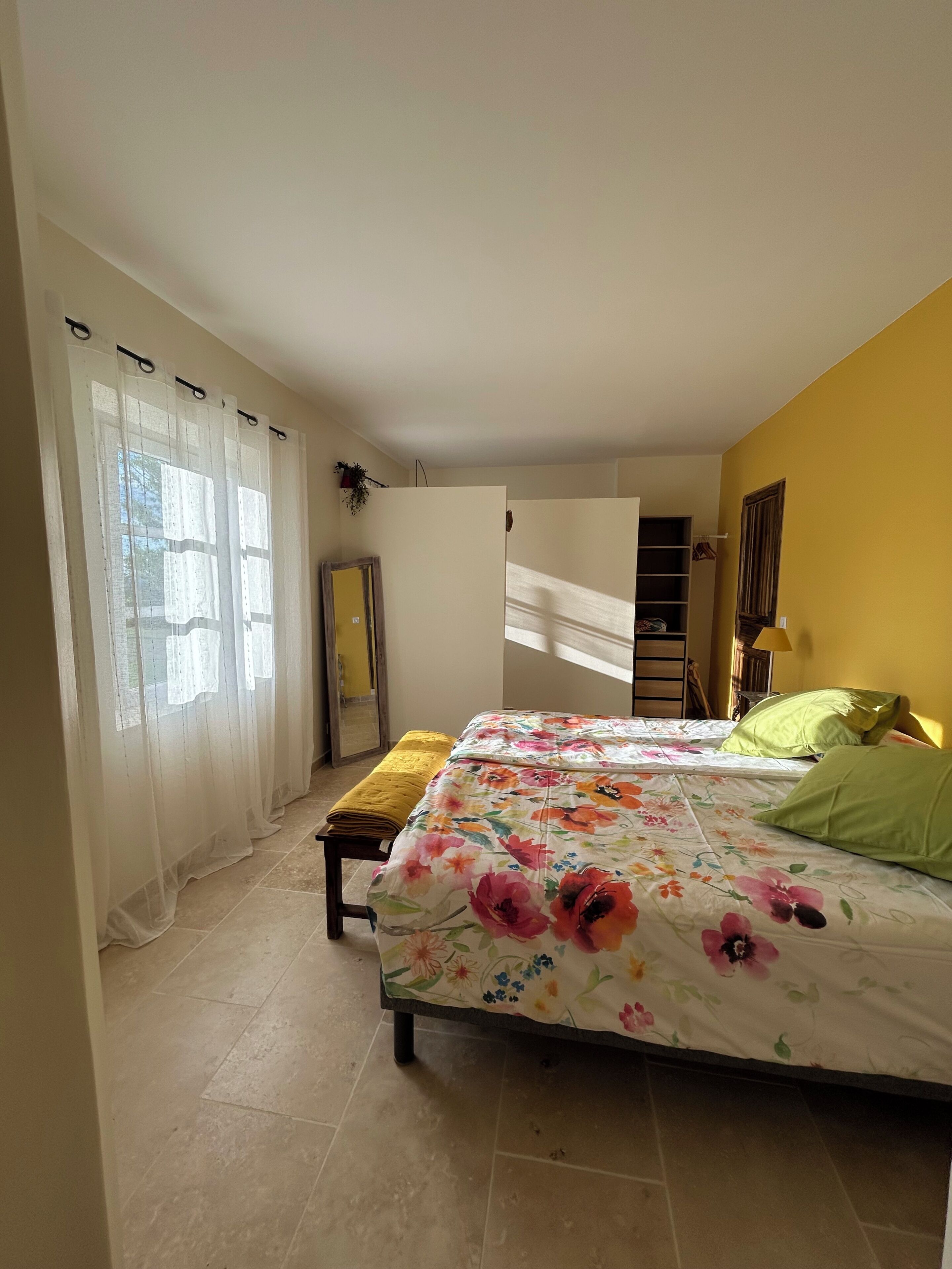 Une chambre à coucher avec un lit, un banc, une armoire et un miroir.