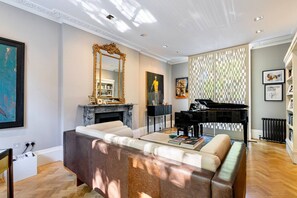 A spacious living room with a grand piano, a fireplace, and a large mirror. - St John s Wood 4-bed House Huge Garden Grand Piano (London)