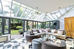 A conservatory with a checkered floor, a sofa set, and a glass table. - St John s Wood 4-bed House Huge Garden Grand Piano (London)