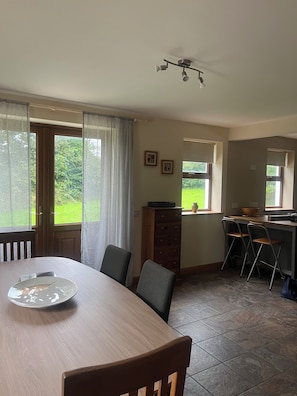 Zona pranzo con tavolo, sedie e vista sull'esterno.