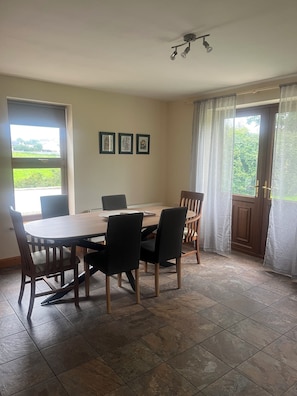 Un coin repas avec une table et des chaises en bois, des tableaux encadrés au mur et une vue par la fenêtre.