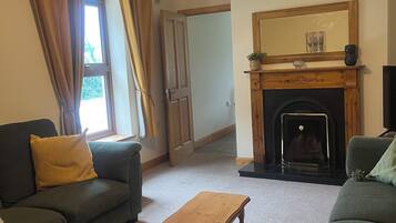 A living room with a fireplace, a sofa, a coffee table, and a door leading to another room.