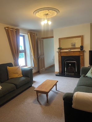 A living room with a fireplace, a sofa, a coffee table, and a door leading to another room.