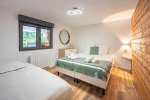 A bedroom with a bed, a bedside table, a mirror, a window, and a wall-mounted light fixture. - La Perle Verte: A luxurious retreat with a pool, spa, and sauna (Gérardmer)