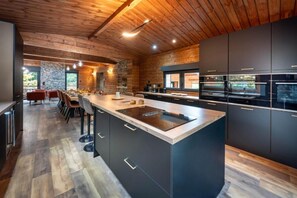 A modern kitchen with a large island, dark cabinetry, and a wooden ceiling. - La Perle Verte: A luxurious retreat with a pool, spa, and sauna (Gérardmer)