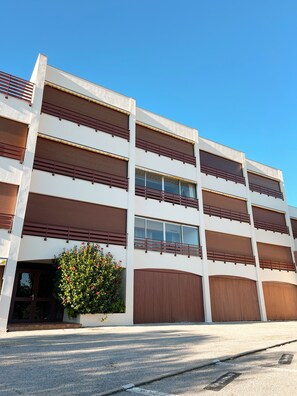 Un immeuble à plusieurs étages, doté d’un toit plat, de grandes fenêtres et d’une entrée centrale avec un petit jardin.
