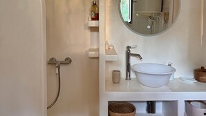 Een badkamer met een bad, een ronde spiegel, een wastafel en een douche.