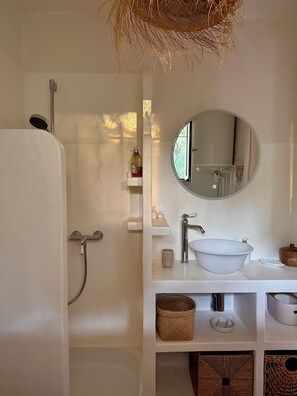 Une salle de bain avec une baignoire, un miroir rond, un lavabo et une douche.