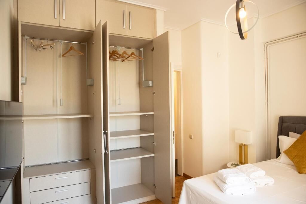 Une chambre d’hôtel comprenant un lit, une table de chevet avec une lampe, une armoire et un porte-manteau.