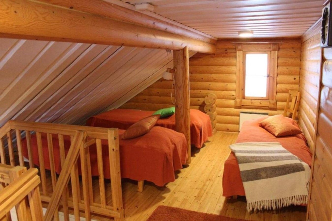 Ein Schlafzimmer in einer Blockhütte mit zwei Betten, einem Fenster und einer Holzbalkendecke.