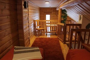 A wooden cabin interior with a cozy seating area, a small table, and a window. - Honkaruka | Homelike 1BR Apt with Private Sauna (Ruka)