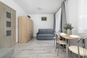 A compact living space with a kitchenette, a dining area, and a sofa. - A Practical Studio Flat with a Balcony | Close to the City Centre (Kraków)
