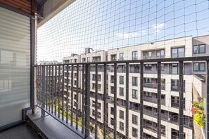 A balcony with a metal railing overlooking a residential building with multiple balconies and windows. - A Practical Studio Flat with a Balcony | Close to the City Centre (Kraków)