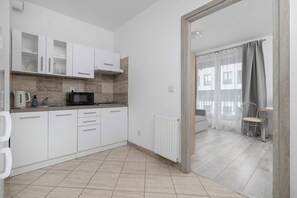 Een moderne keuken met witte kastjes, een Bosch koffiezetapparaat en een magnetron.