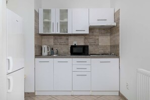 Una cocina moderna con armarios blancos, una cafetera Bosch, un microondas y una máquina de café.