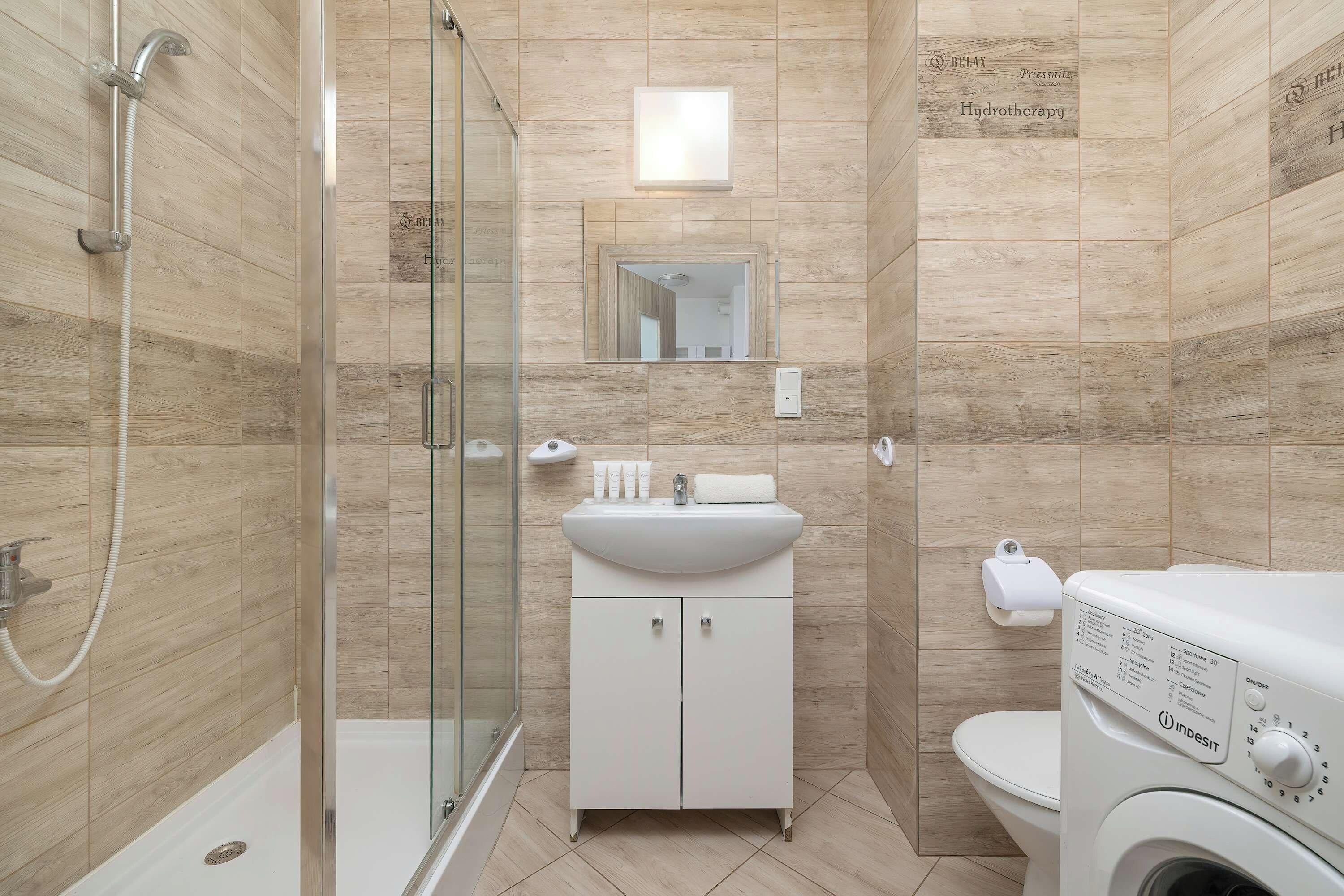 A modern bathroom with a glass shower enclosure, a white sink, and a toilet.