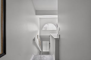 Un pasillo estrecho con pared blanca, suelo de madera y techo blanco.
