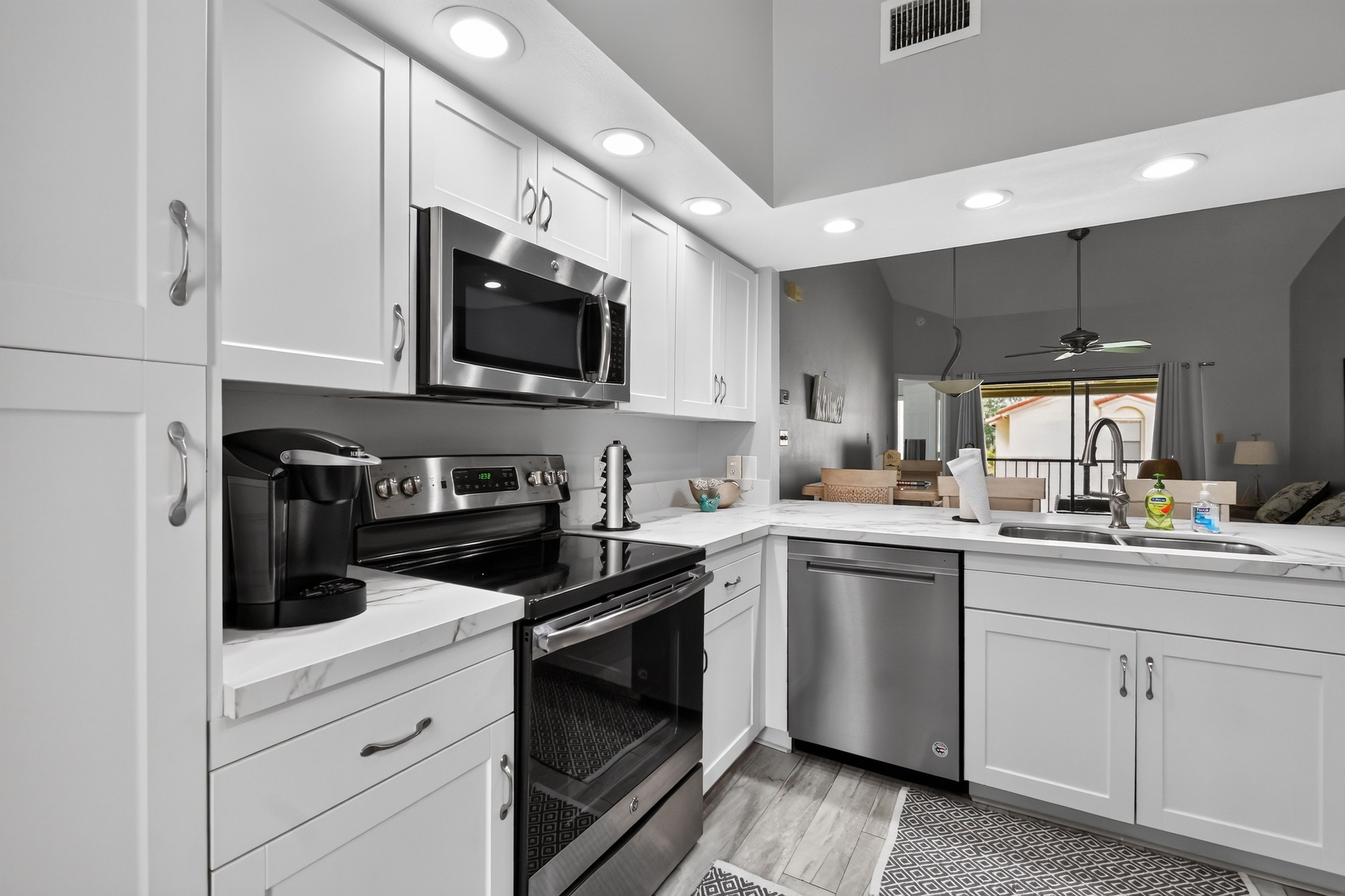 A modern kitchen with white cabinetry, stainless steel appliances, and a built-in oven.