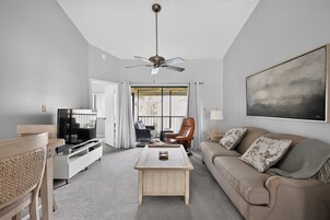 A living room with a sofa, a coffee table, a TV, and a ceiling fan.