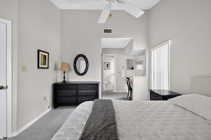 Un dormitorio con cama, cómoda, espejo y ventilador de techo.