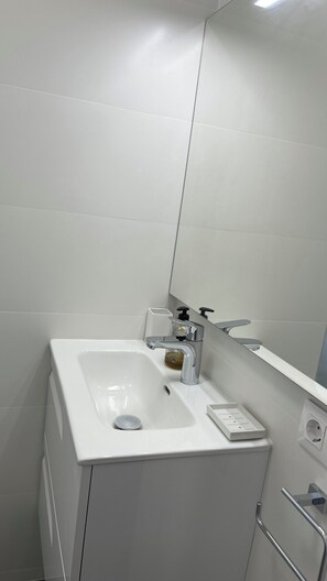 A modern bathroom with a white sink, a mirror, and a towel rack. - Pleasant 2-bedroom apartment with AC in charming CN (CN)