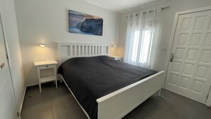 A bedroom with a bed, bedside tables, a nightstand, a painting, and a door. - Pleasant 2-bedroom apartment with AC in charming CN (CN)