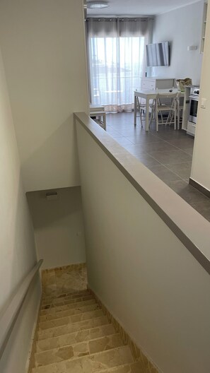 A staircase leading to a room with a kitchen area, a dining table, and a television. - Pleasant 2-bedroom apartment with AC in charming CN (CN)