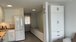A compact kitchen with white cabinetry, a refrigerator, and a sink. - Pleasant 2-bedroom apartment with AC in charming CN (CN)