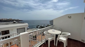 A balcony with a table and chairs, overlooking a coastal view with rocks and the sea. - Pleasant 2-bedroom apartment with AC in charming CN (CN)