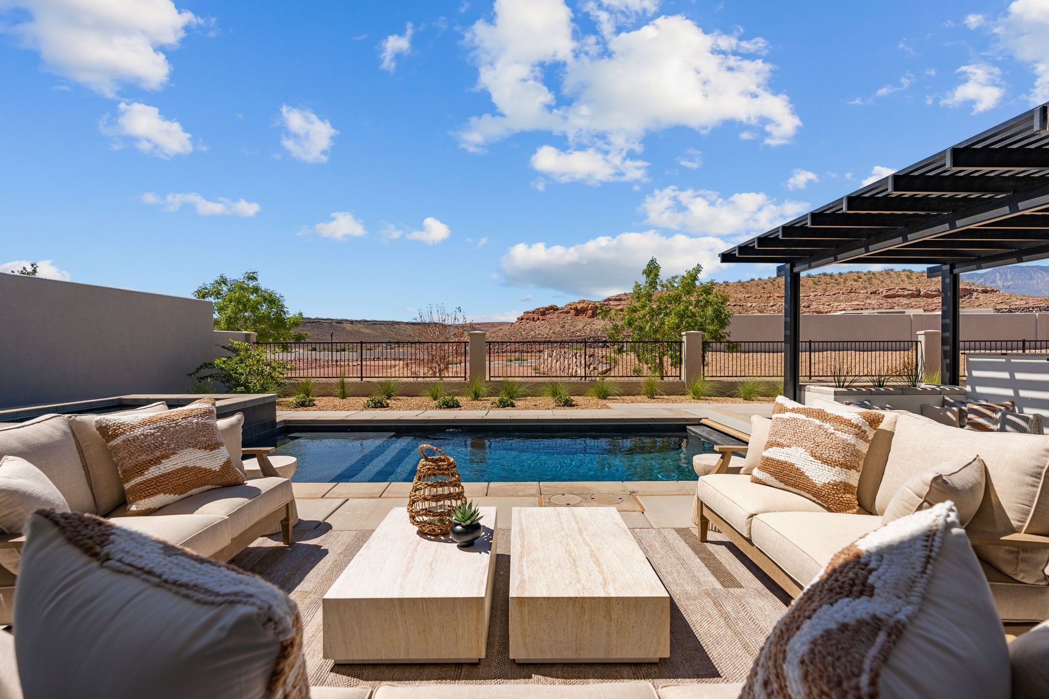 A poolside area with outdoor seating and a view of a mountainous landscape.